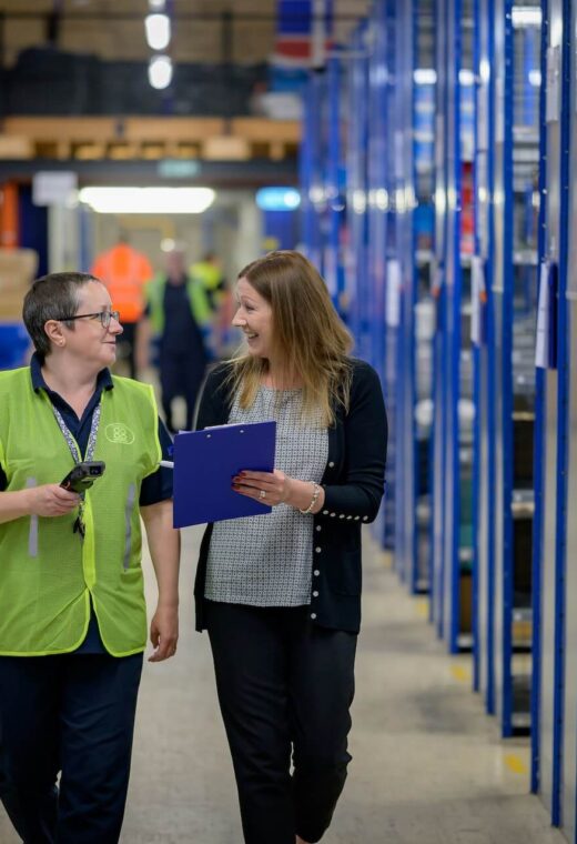 Two staff members in a warehouse discussing job uncertainty for warehouse staff