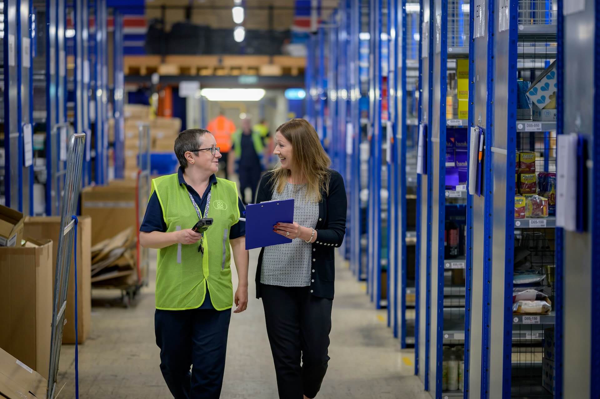 Two staff members in a warehouse discussing job uncertainty for warehouse staff